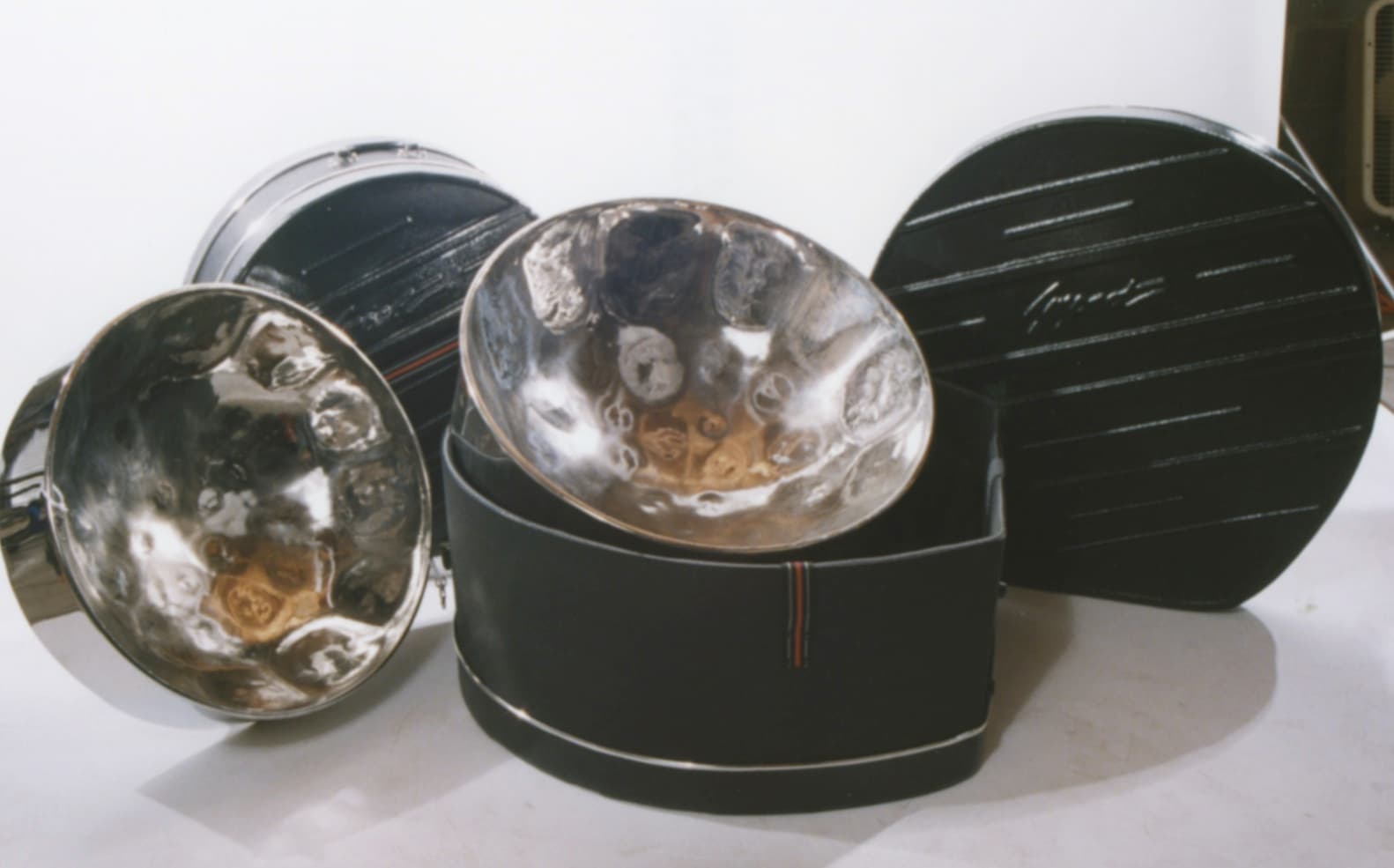 Polished steel drums in their cases, showing the chrome surfaces and note layout